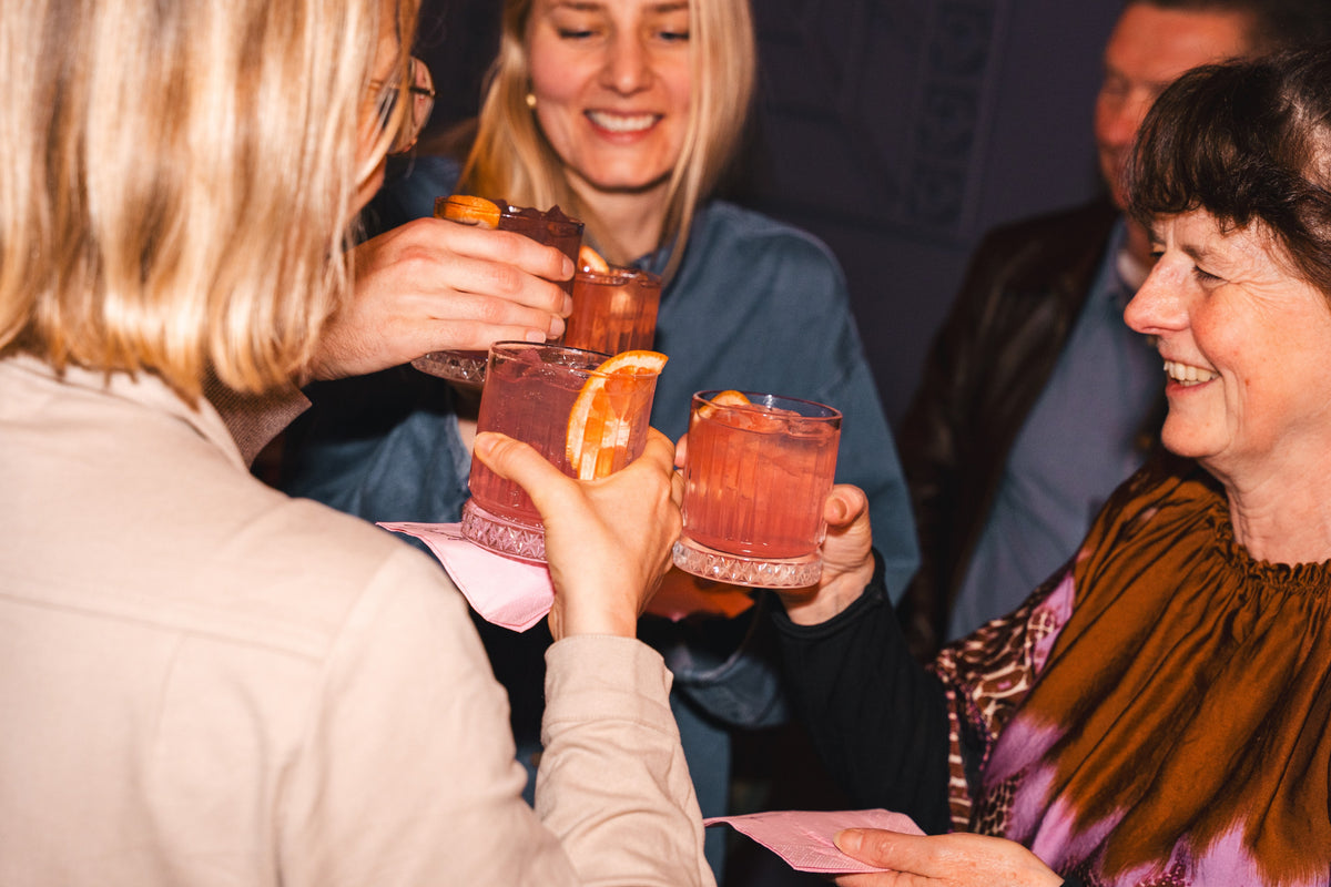 Freunde stoßen in einer Bar mit rosa Drinks und Grapefruit an