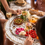  Ein gedeckter Tisch mit alkoholfreiem French Bloom Schaumwein, frischem Gemüse, Oliven, Käse und Brot, der eine gesellige und luxuriöse Atmosphäre zeigt.