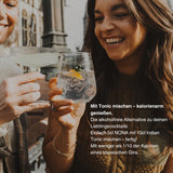 Zwei Frauen stoßen mit Cocktails an, die mit NONA gemischt wurden, und genießen den alkoholfreien Aperitif. Der Text im Bild erklärt das einfache Mischverhältnis und die geringe Kalorienanzahl des alkoholfreien Aperitifs.


