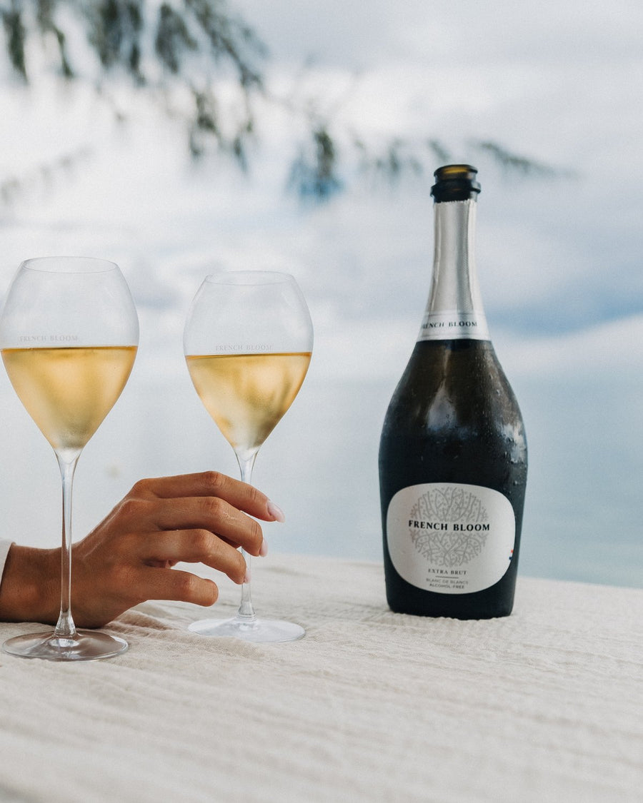 Eine Flasche French Bloom mit zwei eingeschenkten Gläsern im Sonnenlicht